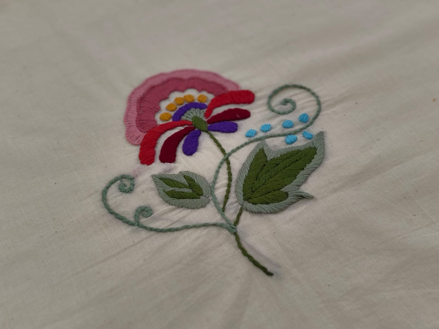 Embroidered flower design on a beige fabric background