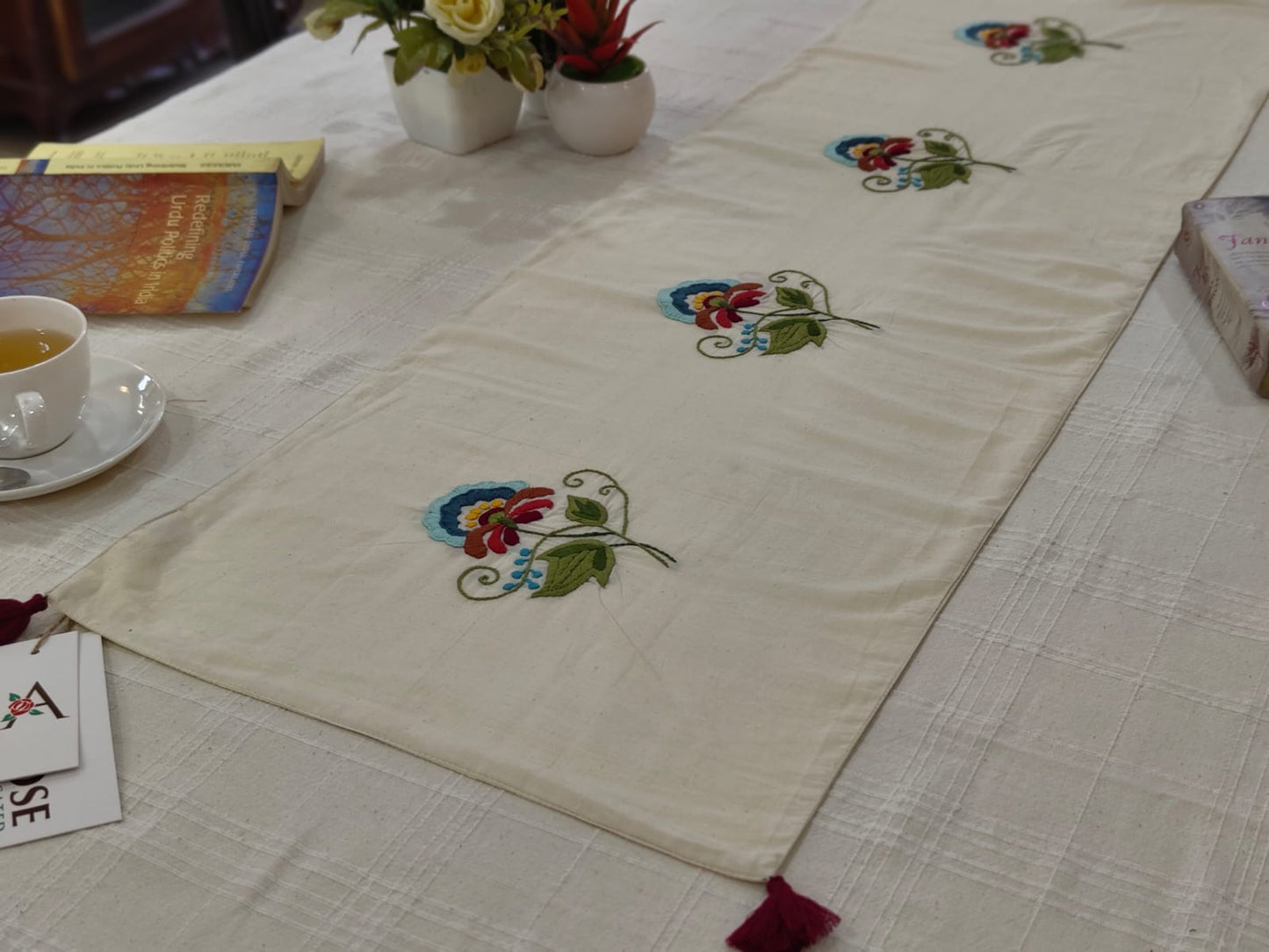 Embroidered table runner with floral patterns on a dining table.
