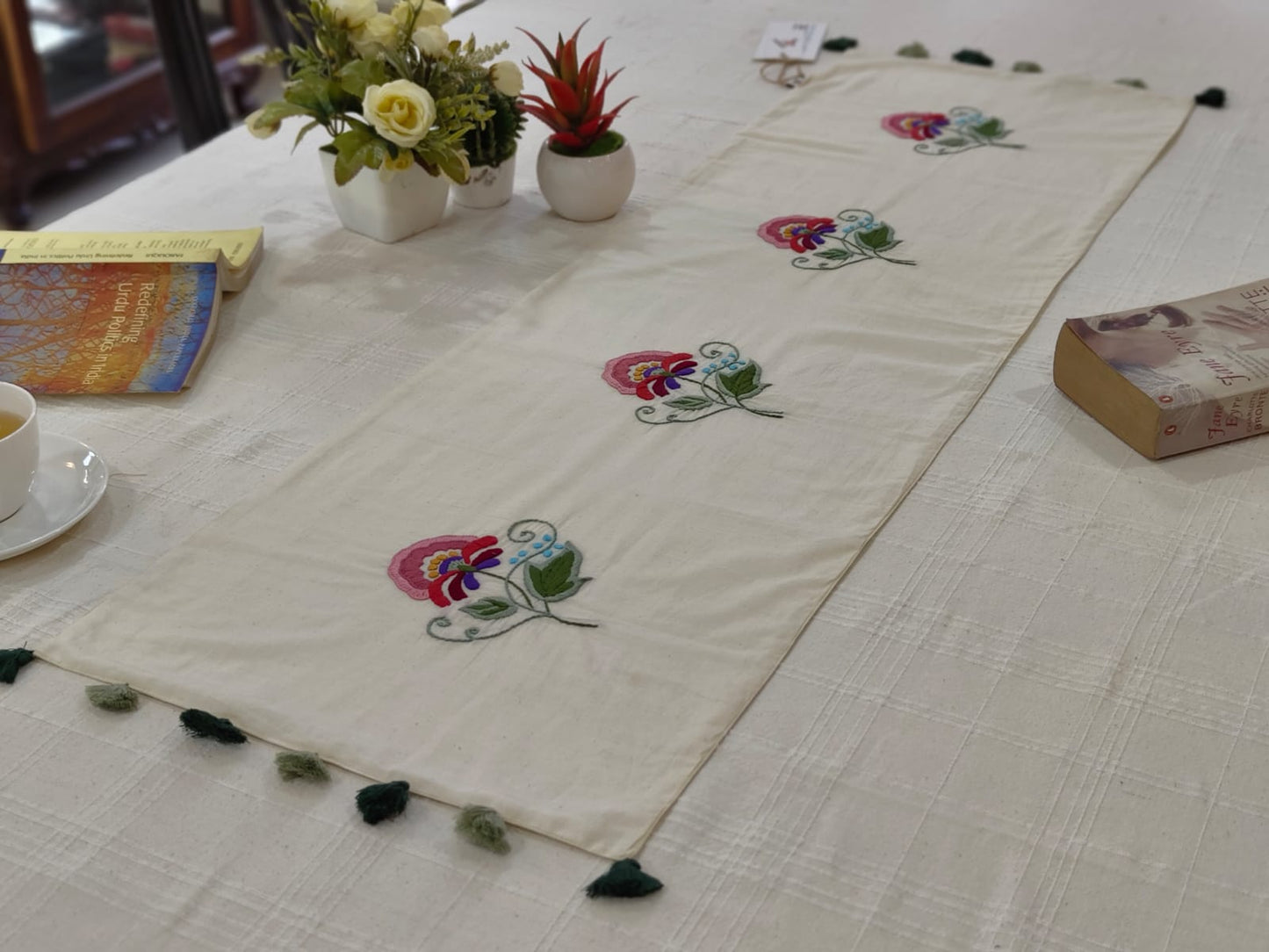 Embroidered table runner with floral designs on a table setting.